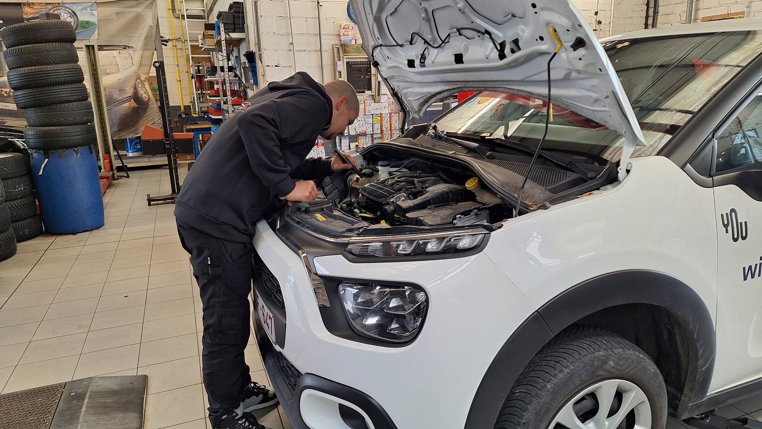 Adam, hoofdmecanicien bij Garage Peter, voert onderhoud uit aan de motor van een wagen