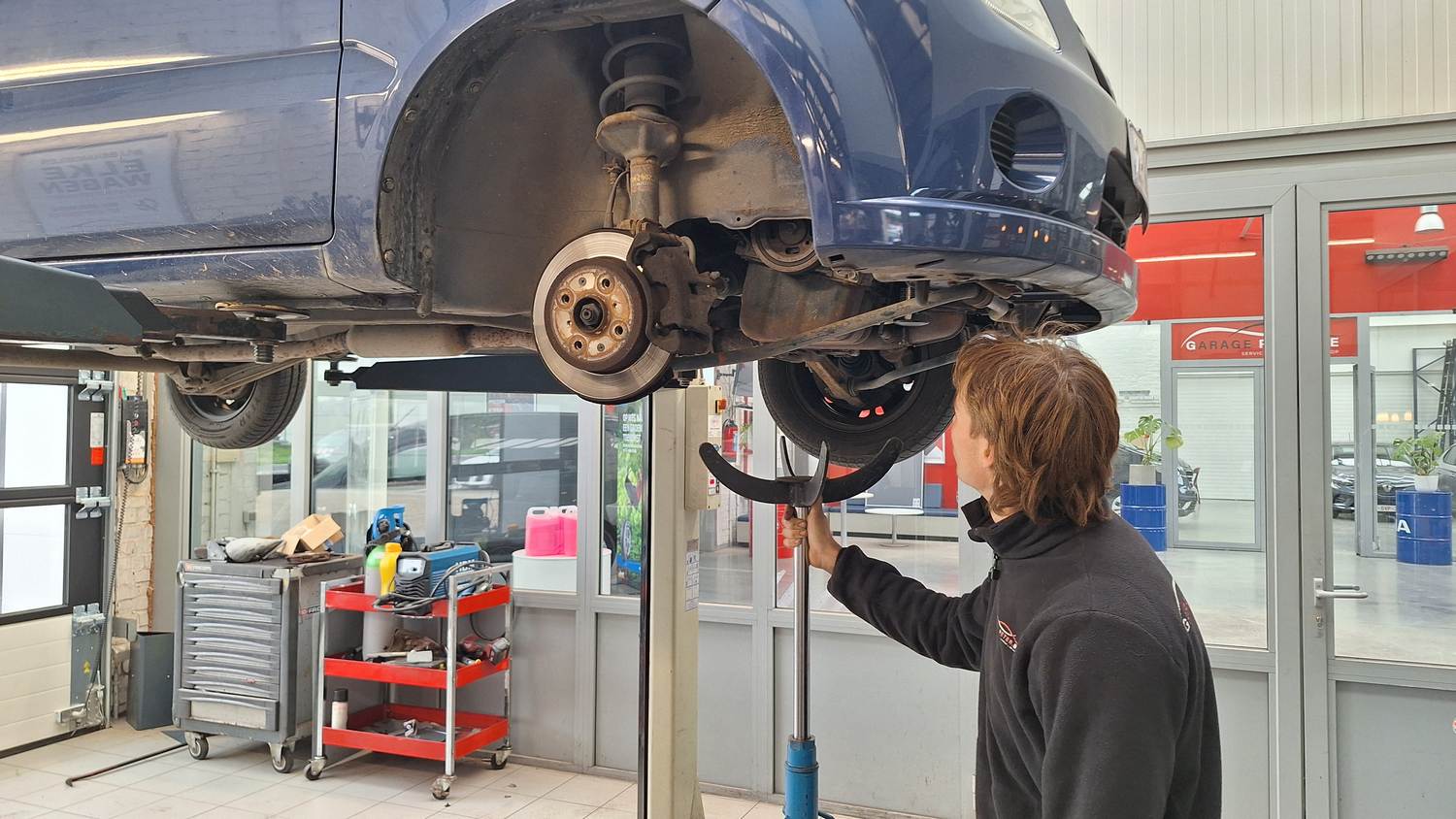 Thomas voert werkzaamheden uit aan een auto op de hefbrug bij Garage Peter in Bredene