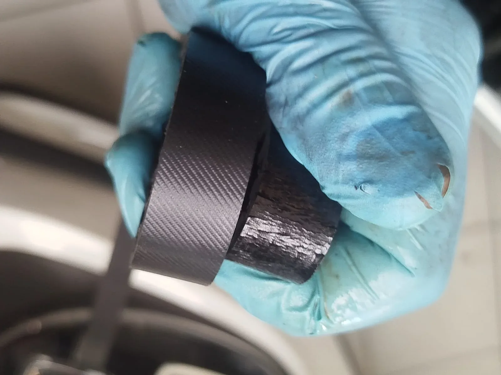 Vergelijking van een riem met gelijkmatig oppervlak en een zwaar aangetaste PureTech-distributieriem met zichtbare barsten bij Garage Peter in Bredene